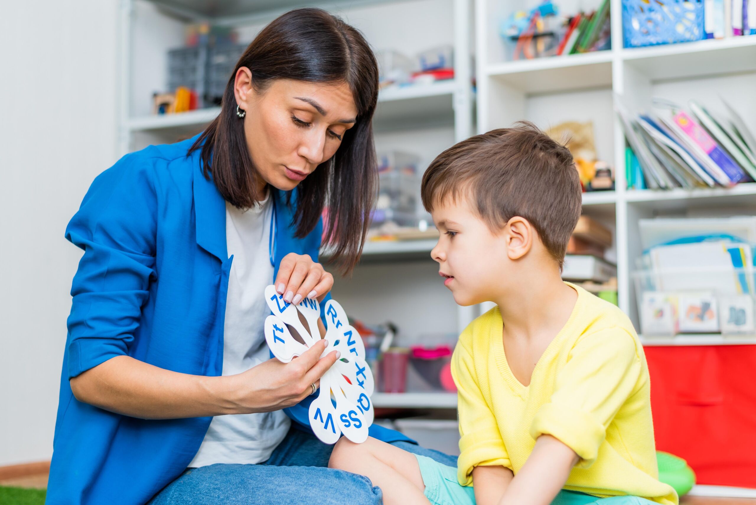 A cute boy with a speech therapist is taught to pronounce the letters, words and sounds.